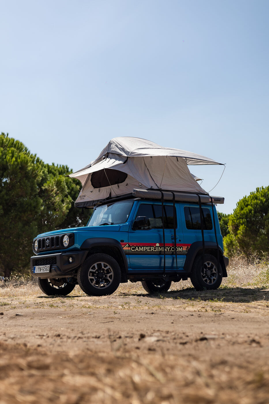 Blue Suzuki Jimny in profile with the roof top tent set up