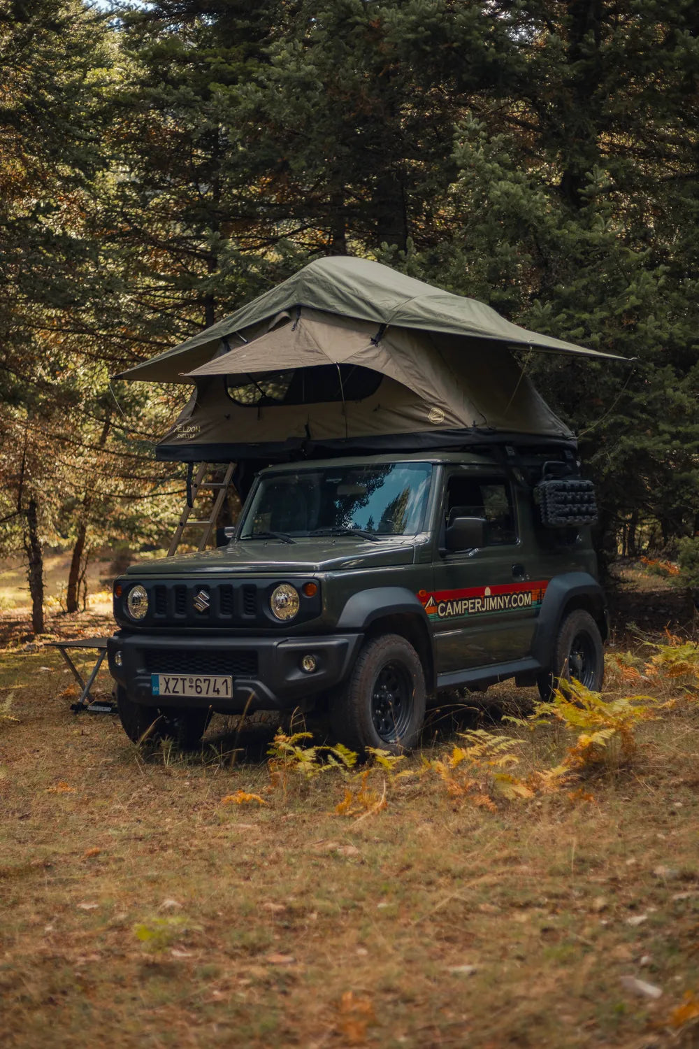Green Suzuki Jimny with the Feldon Shelter Crow's Nest roof top tent open among pine trees in Greece