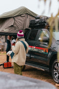 Travellers at camp beside a Suzuki Jimny with its roof top tent open