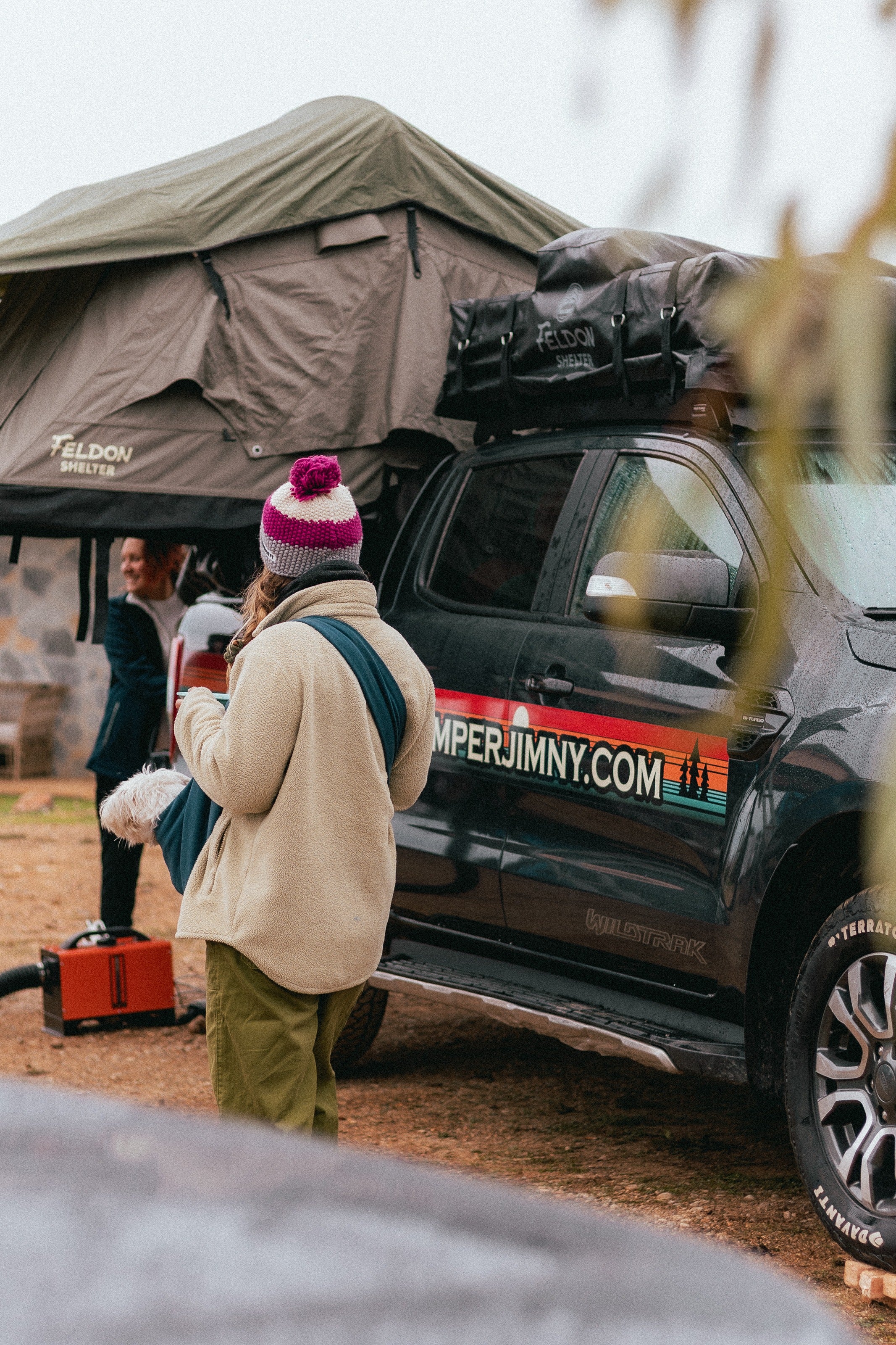 Travellers at camp beside a Suzuki Jimny with its roof top tent open