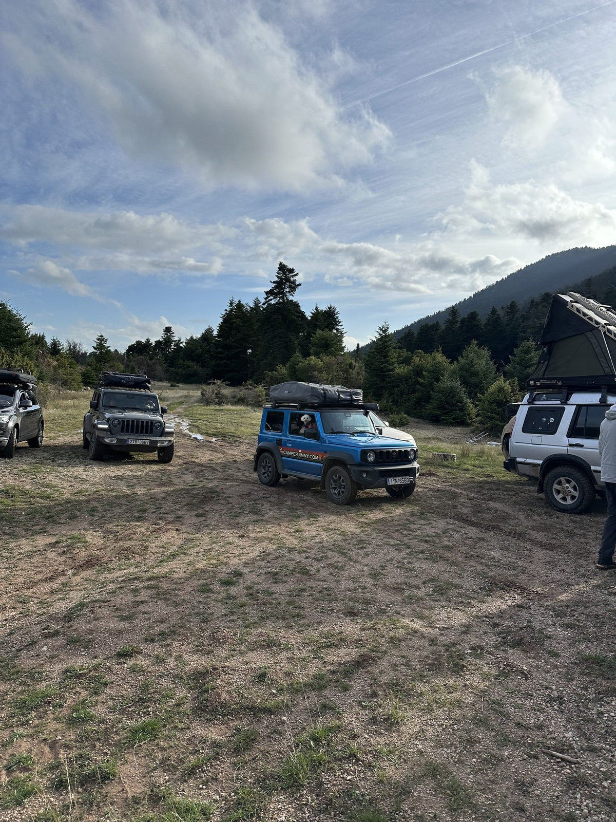 A convoy of 4x4s parked at a mountain clearing with roof top tents up
