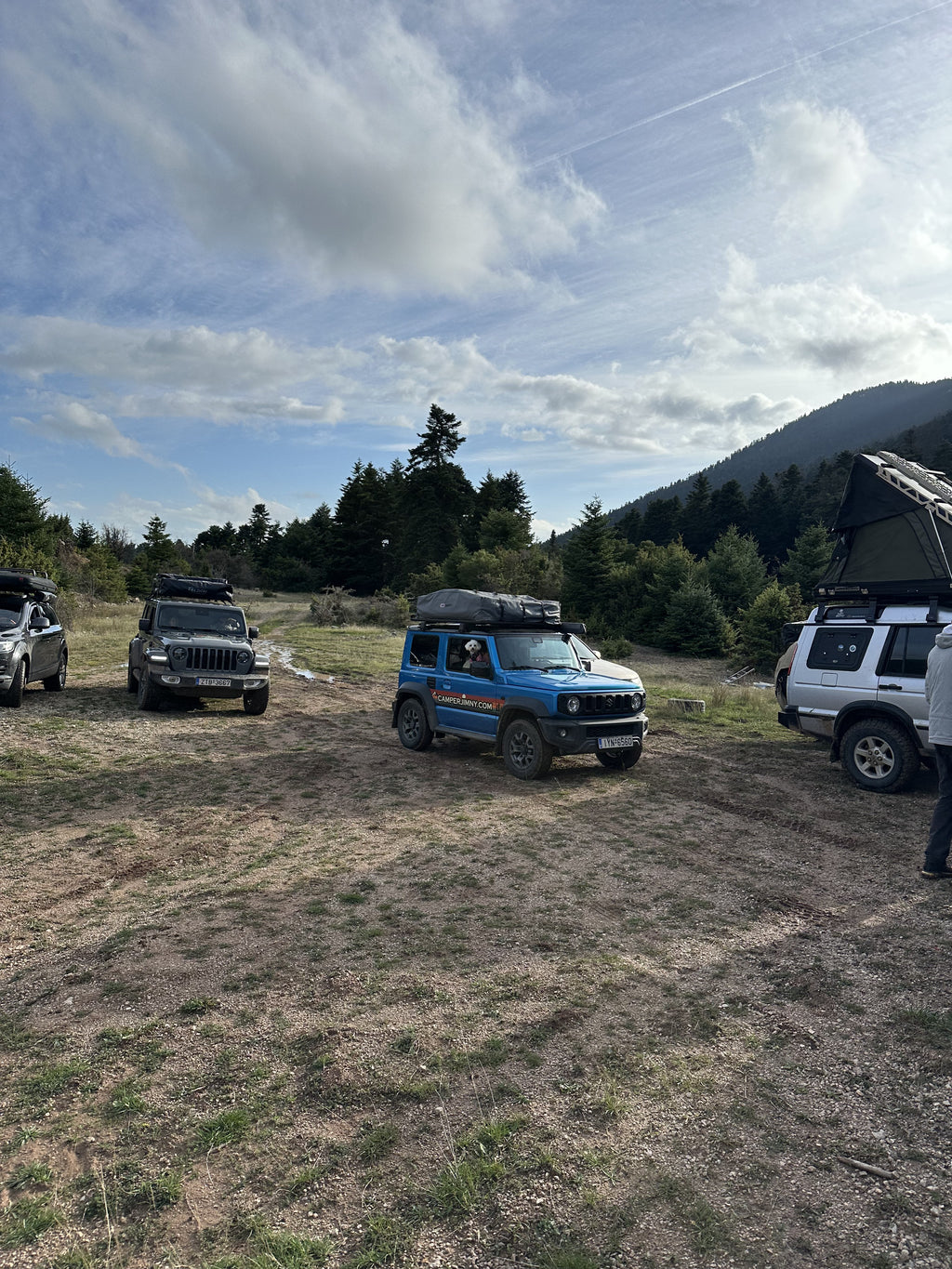 A convoy of 4x4s parked at a mountain clearing with roof top tents up