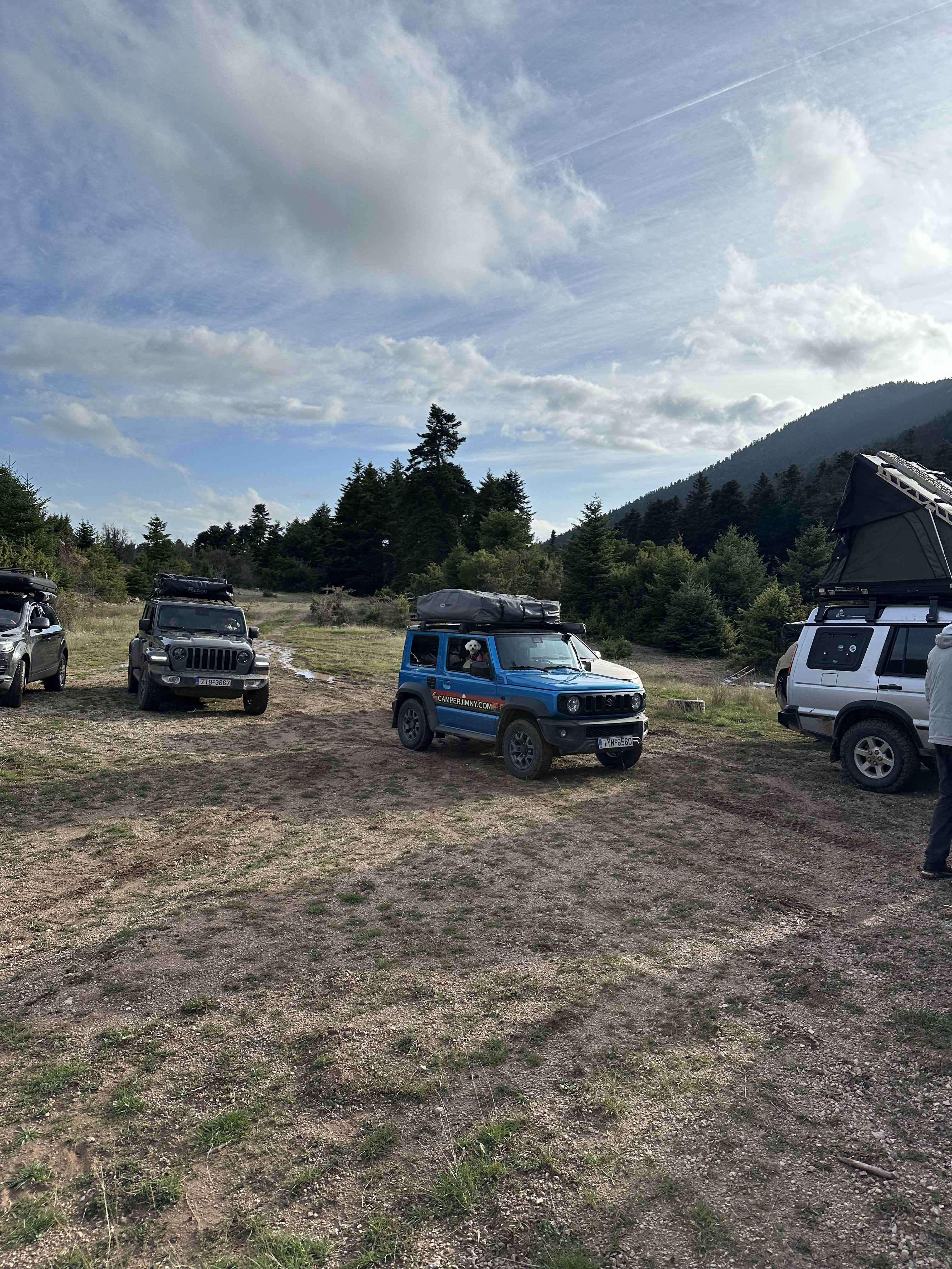 A convoy of 4x4s parked at a mountain clearing with roof top tents up